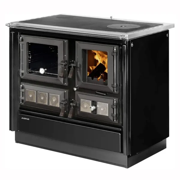 En moderne sort Justus Rustico 90 2.0 peisovn plassert til høyre, med blank sort emalje, doble glassfronter mot ildkasser—en med livlige flammer og vedstokker—og en flat koketoppflate. Plassert i et koselig rom med tregulv, et spisebord med hvite stoler, et vindu med naturlig lys og en kurv med ved i nærheten.
